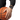 A close-up of a person's hand resting on an orange basketball while wearing a black chronograph wristwatch with a black strap and black bezel, set against a plain white background.