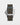 reverse layout of a dark brown, grey, and beige striped polyamide NATO strap highlighting the sandblasted titanium pin buckle clasp engraved with the Omega insignia
