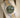 Angled display view of the 2026 Rolex Datejust 36 126233 resting on a cushion, showing the olive green dial, gold Roman numerals, and two-tone Jubilee bracelet