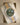 Angled display view of the 2026 Rolex Datejust 36 126233 resting on a cushion, showing the olive green dial, gold Roman numerals, and two-tone Jubilee bracelet