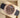 An angled top-down view of a solid 18k rose gold Rolex Sky-Dweller 326235 chocolate dial watch resting on a beige leather display cushion